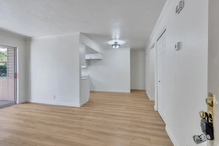 Open-concept living area featuring wood-finish flooring, white walls, and a sliding glass door