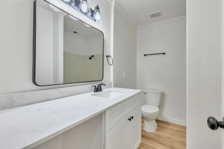 Bathroom with white vanity cabinet, integrated sink, and light-toned countertop