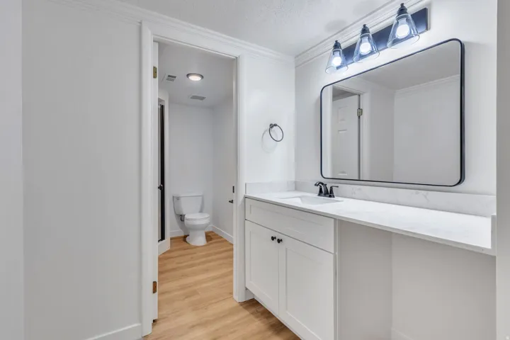 Bathroom vanity with white cabinetry, a white countertop, and a rectangular mirror with a matte black frame