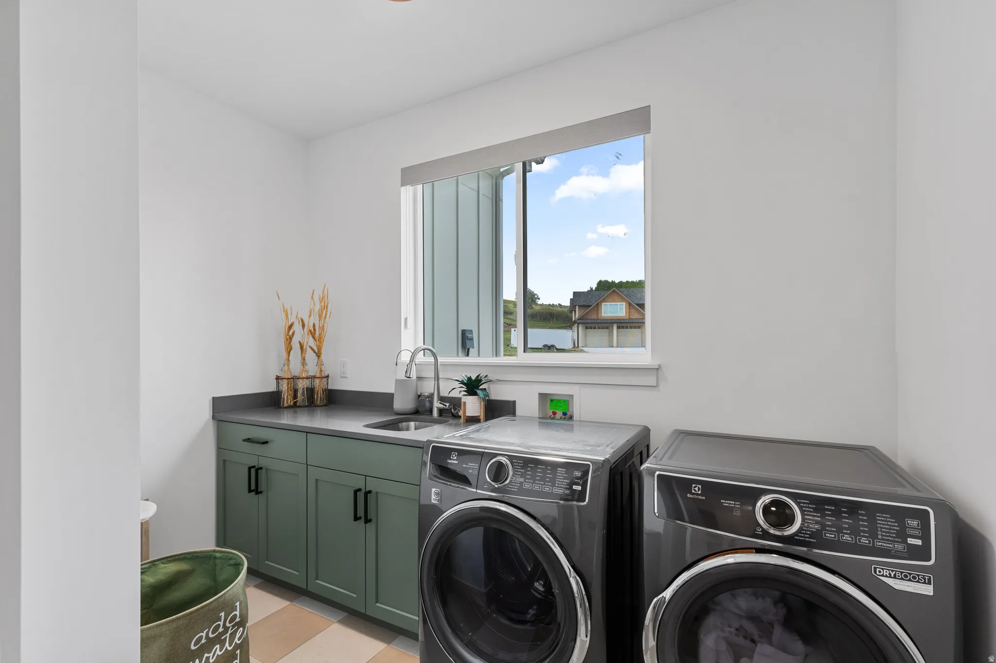 Utility room featuring a window, built-in cabinetry with dark green shaker doors, a countertop with an undermount sink, and a chrome gooseneck faucet