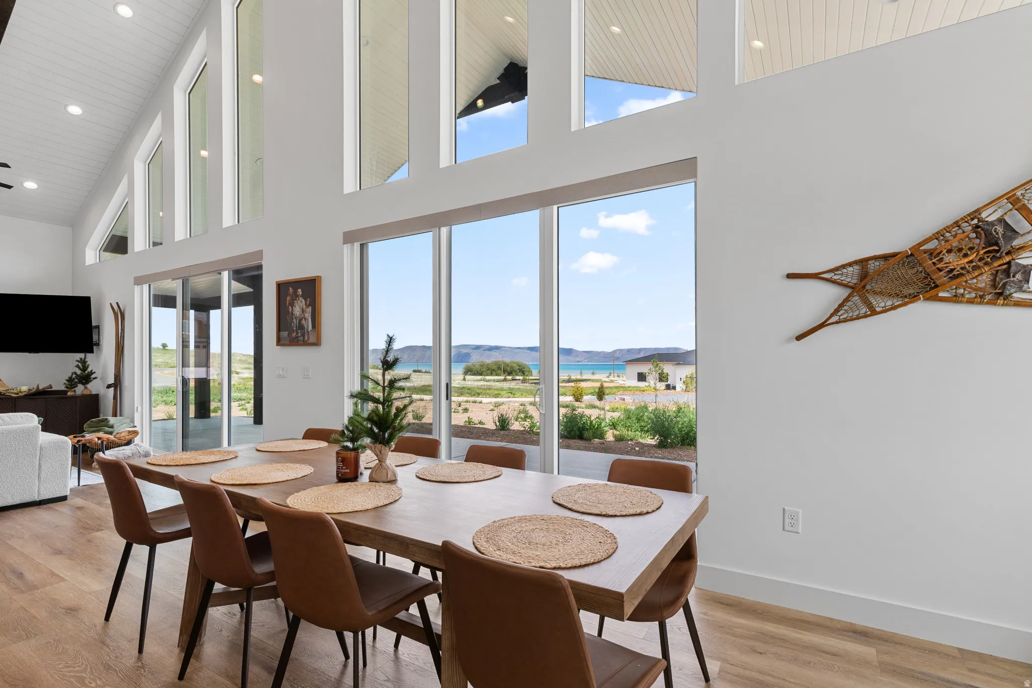 Expansive dining area featuring a long wooden table, wood-finish flooring, and a vaulted ceiling with recessed lighting
