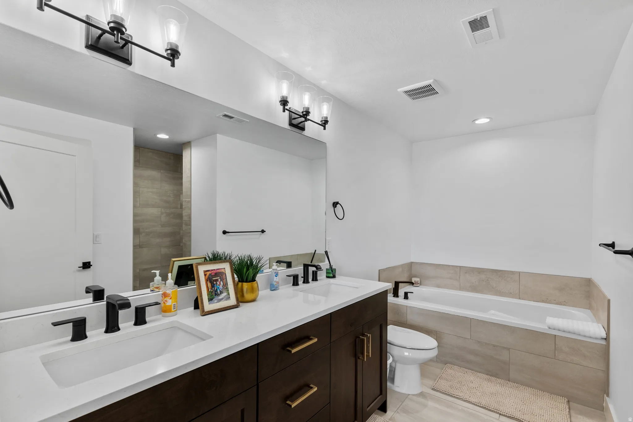 Bathroom featuring a dual vanity with white countertops, dark wood cabinetry, and matte black fixtures
