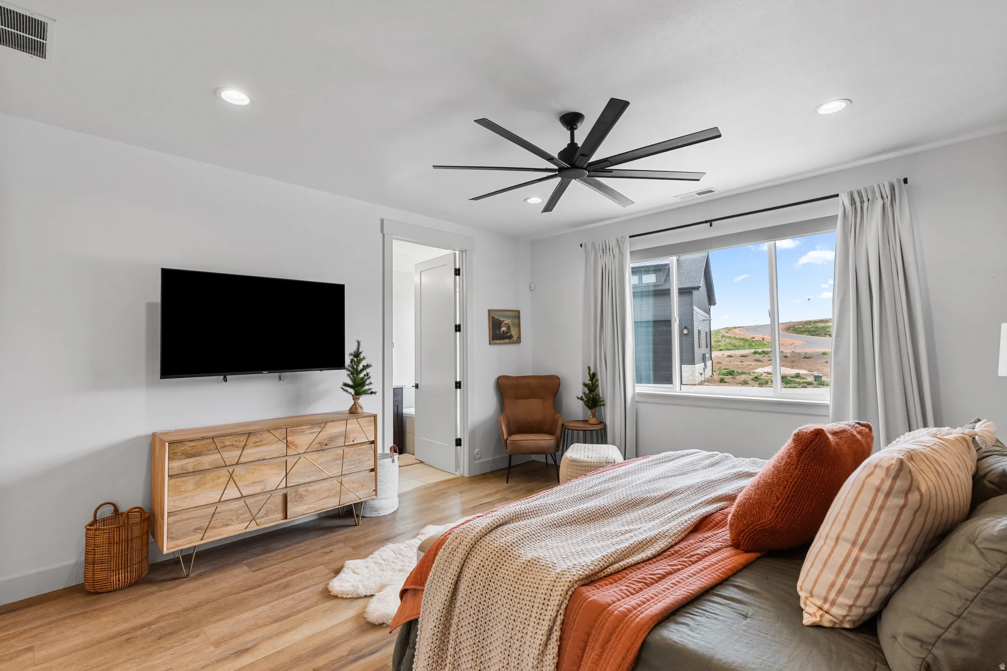 Spacious room featuring wood-finish flooring, a contemporary ceiling fan, recessed lighting, and expansive windows
