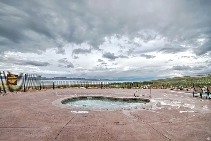 Outdoor spa with a concrete surround and integrated steps, offering expansive water and distant mountain scenery