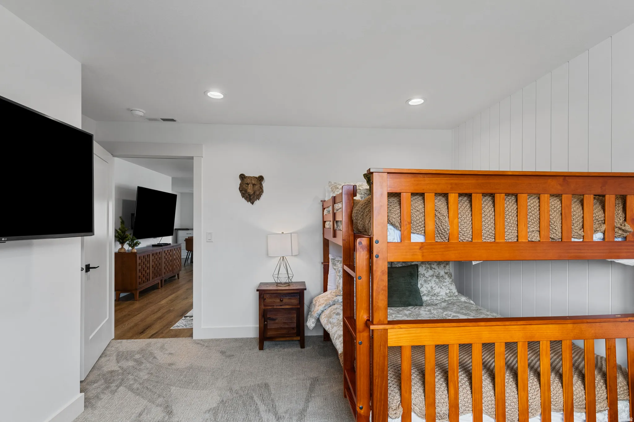 Bedroom featuring recessed lighting, a mounted flat-screen television, light gray carpeting, and a wood-finish bunk bed frame