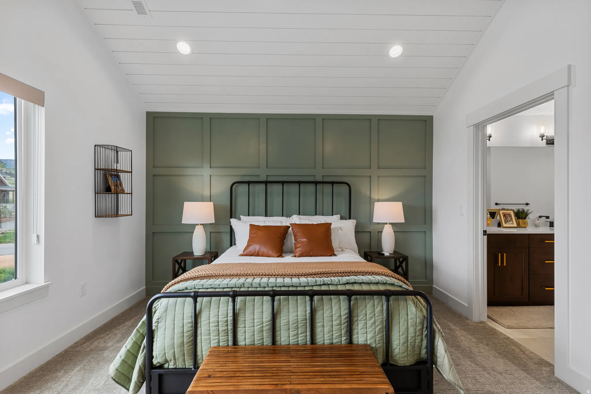 Bedroom with a paneled accent wall, a tray ceiling featuring recessed lighting, and a large window with a roller shade