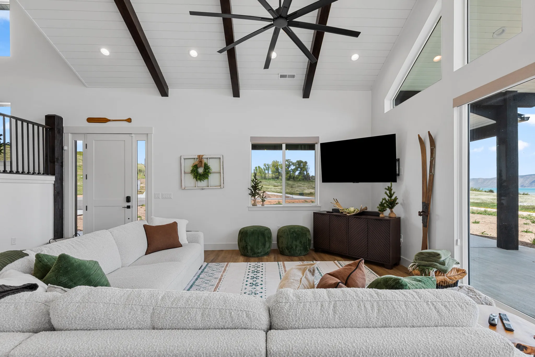 Spacious living area featuring a vaulted ceiling with exposed dark wood beams and recessed lighting