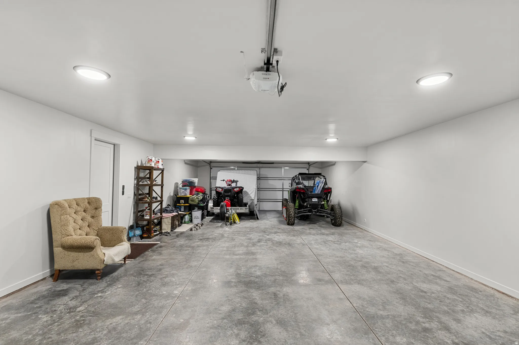 Spacious garage featuring a concrete floor, bright overhead lighting, and a white overhead garage door