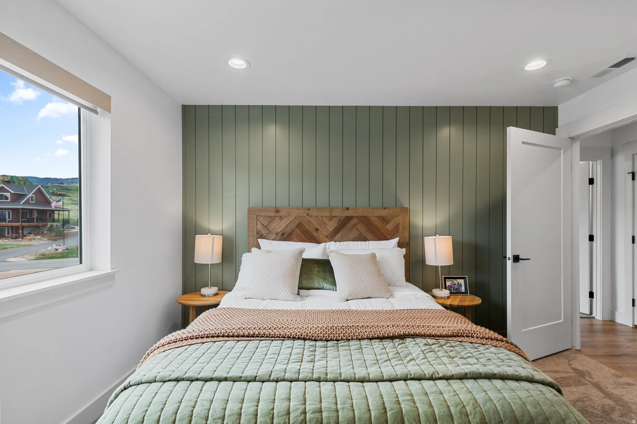 Bedroom featuring a vertical wood panel accent wall, recessed lighting, and a window with a broad sill