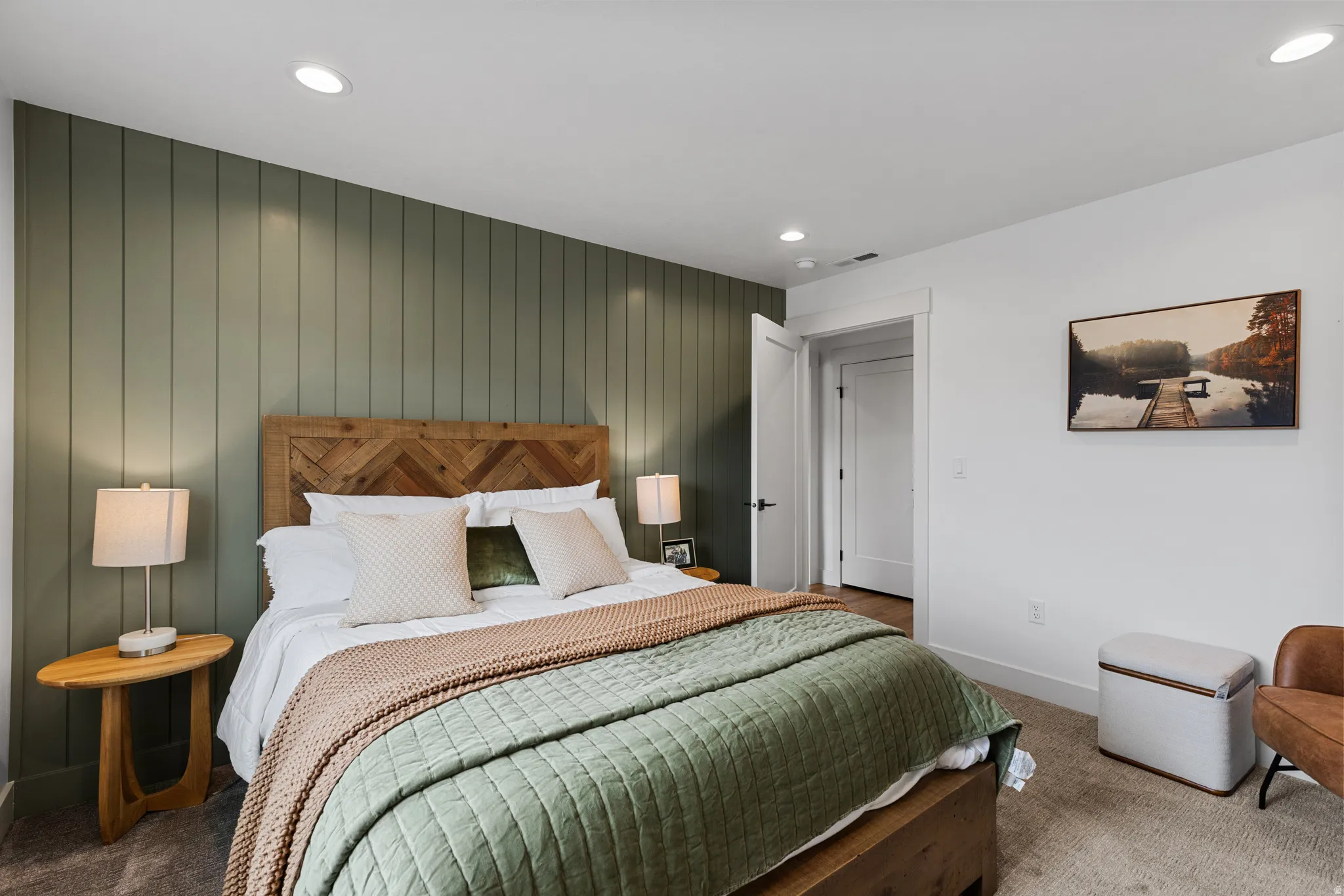Bedroom featuring a vertical paneled accent wall, recessed ceiling lighting, and a neutral carpeted floor
