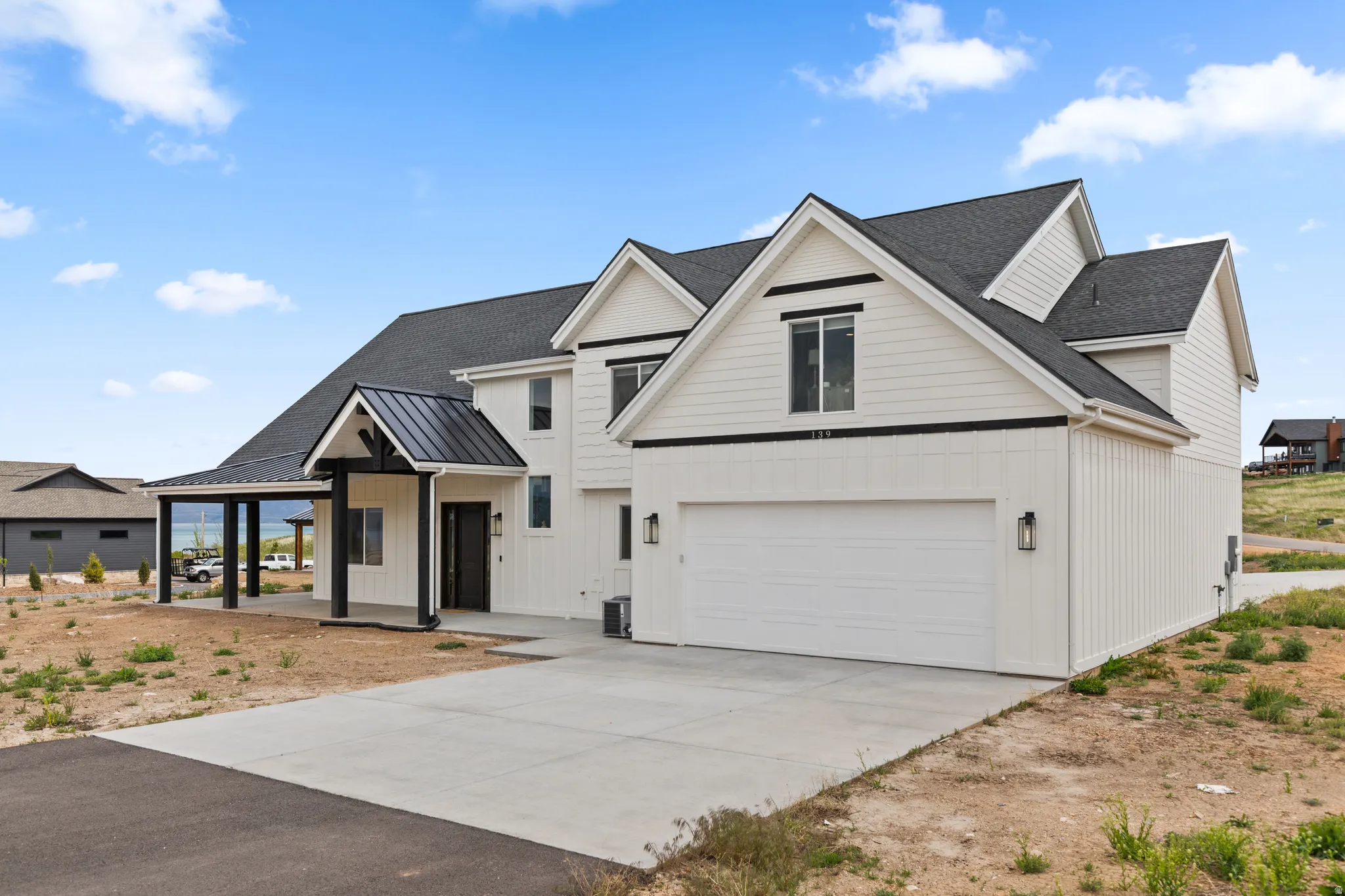 Contemporary farmhouse exterior featuring white board and batten siding, a dark asphalt shingle roof, and an attached two-car garage