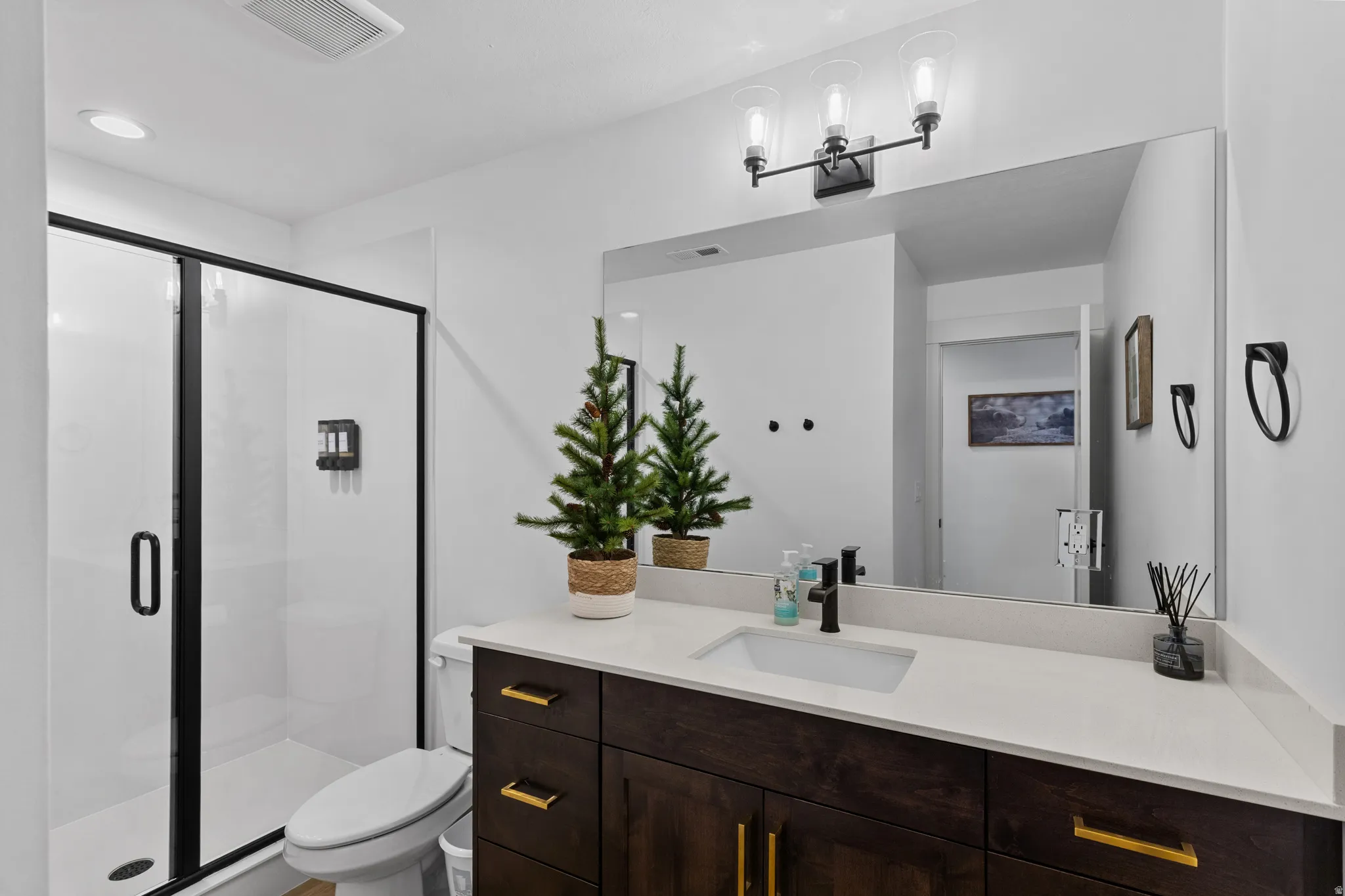 Bathroom featuring a dark wood-finish vanity with gold-tone hardware, a white countertop, and a rectangular undermount sink with a matte black faucet
