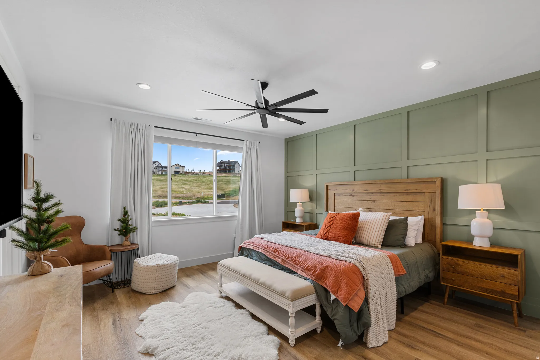 Bedroom featuring a panel accent wall, wood-finish flooring, a large window, and recessed lighting