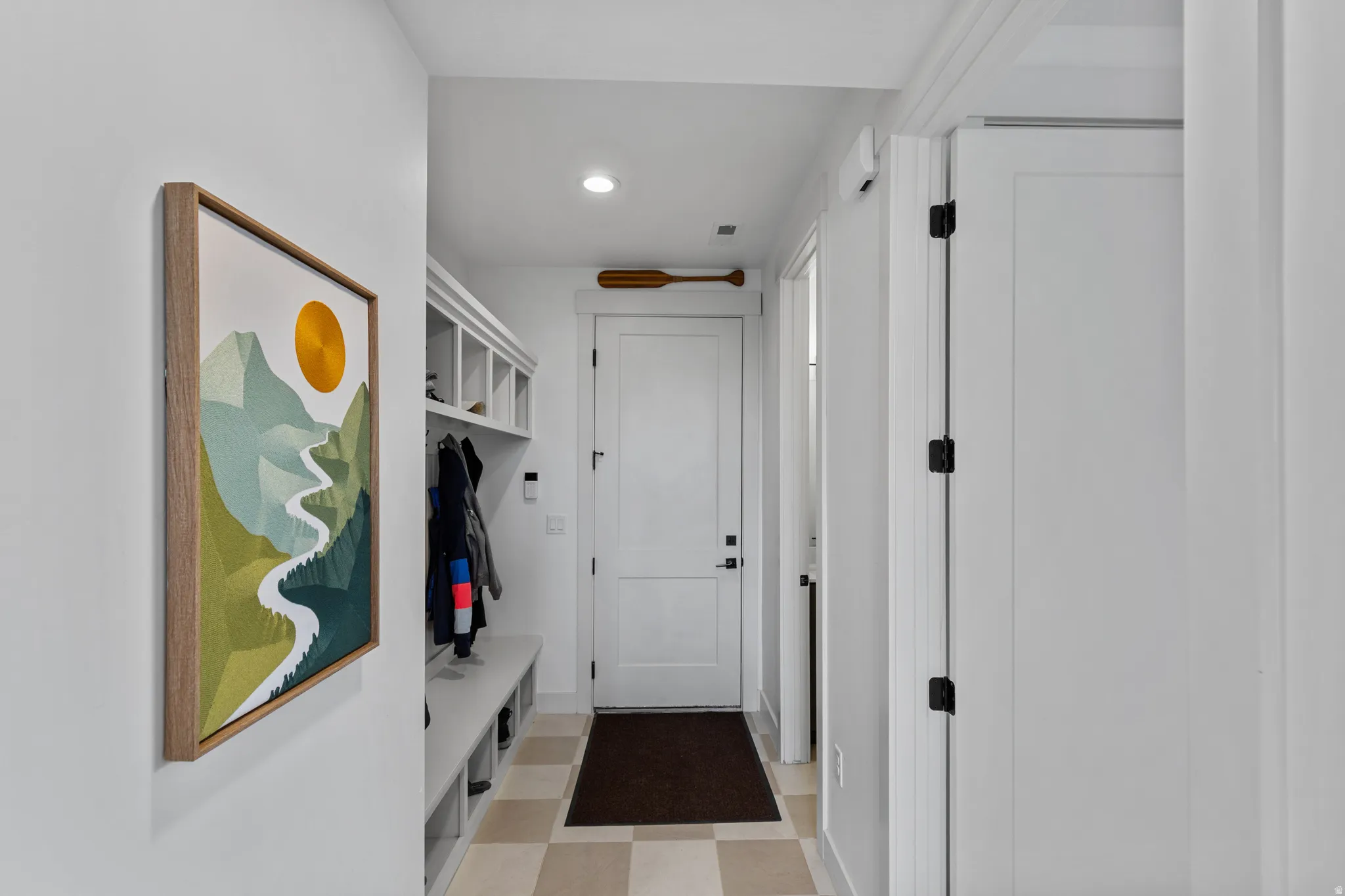 Mudroom featuring built-in bench seating, upper cubbies, and coat hooks