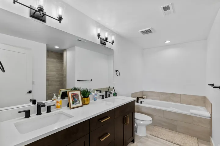 Bathroom featuring a dual vanity with white countertops, dark wood cabinetry, and matte black fixtures