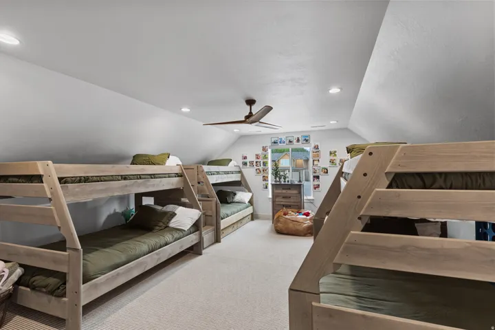 Vaulted ceiling room featuring multiple bunk beds with integrated stairs, recessed lighting, and a ceiling fan