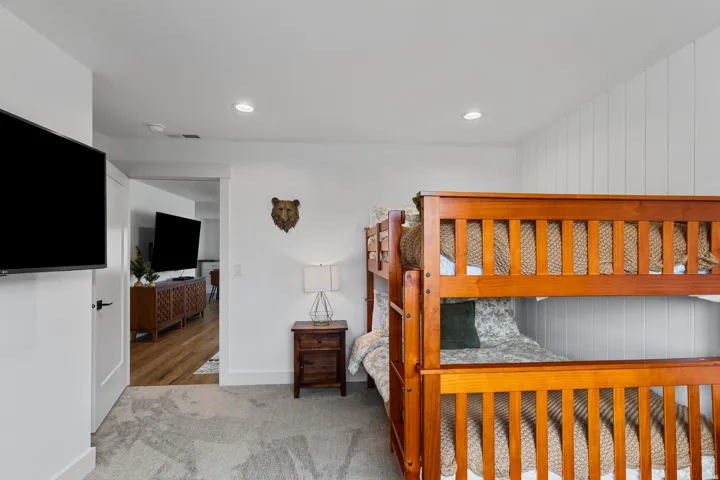 Bedroom featuring recessed lighting, a mounted flat-screen television, light gray carpeting, and a wood-finish bunk bed frame