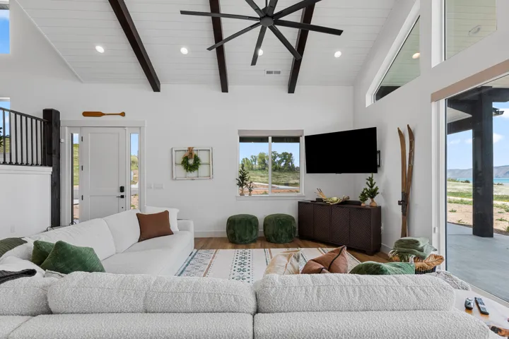 Spacious living area featuring a vaulted ceiling with exposed dark wood beams and recessed lighting