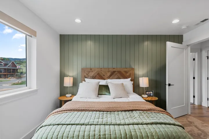 Bedroom featuring a vertical wood panel accent wall, recessed lighting, and a window with a broad sill