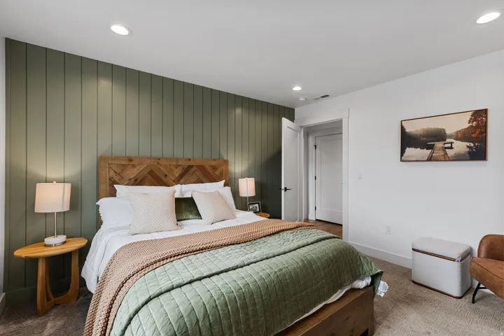 Bedroom featuring a vertical paneled accent wall, recessed ceiling lighting, and a neutral carpeted floor