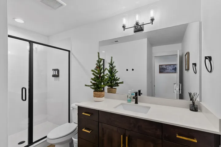 Bathroom featuring a dark wood-finish vanity with gold-tone hardware, a white countertop, and a rectangular undermount sink with a matte black faucet