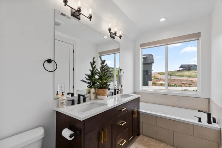 Dual sink vanity with dark wood-finish cabinetry, gold-tone hardware, and white countertops