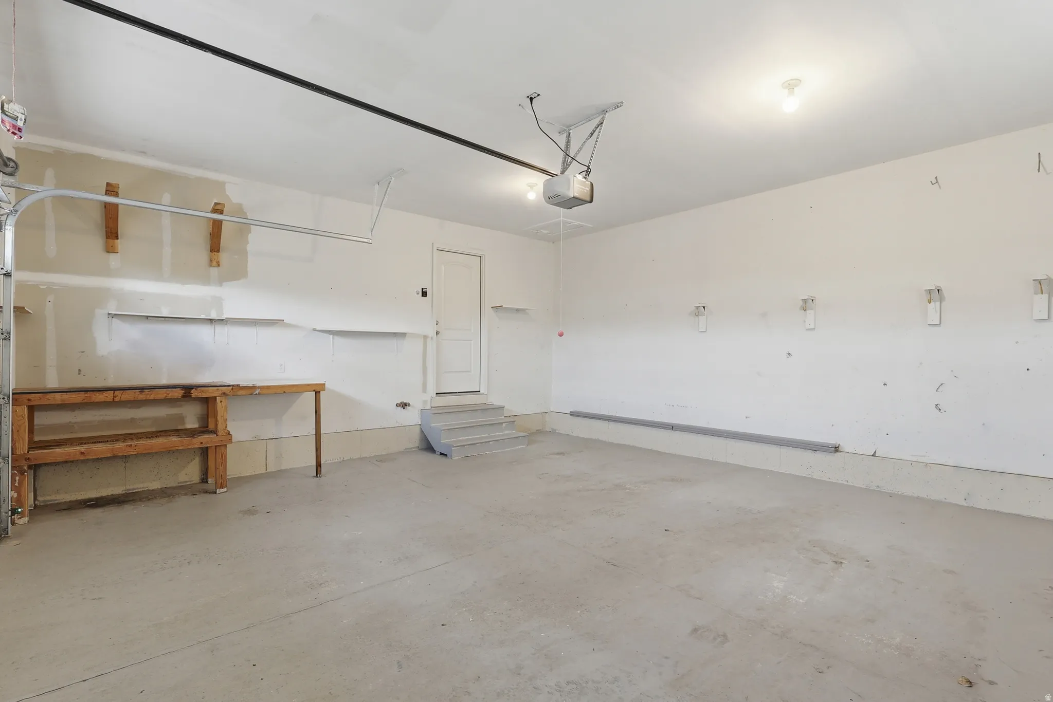 Spacious garage featuring a concrete floor, overhead lighting, 2 large windows and an automatic garage door opener.