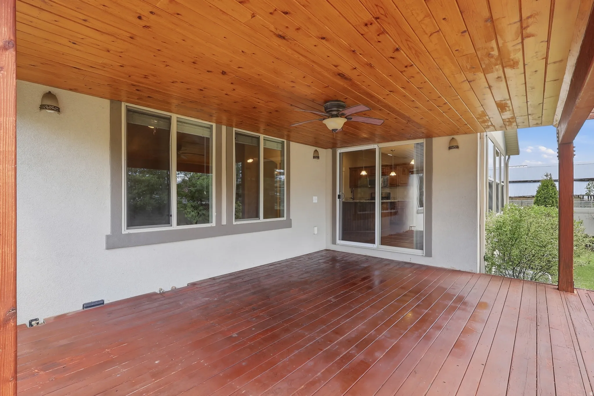 Expansive covered deck featuring a wood- ceiling and ceiling fan, recessed lighting, and a sliding glass door leading from the kitchen dining area.