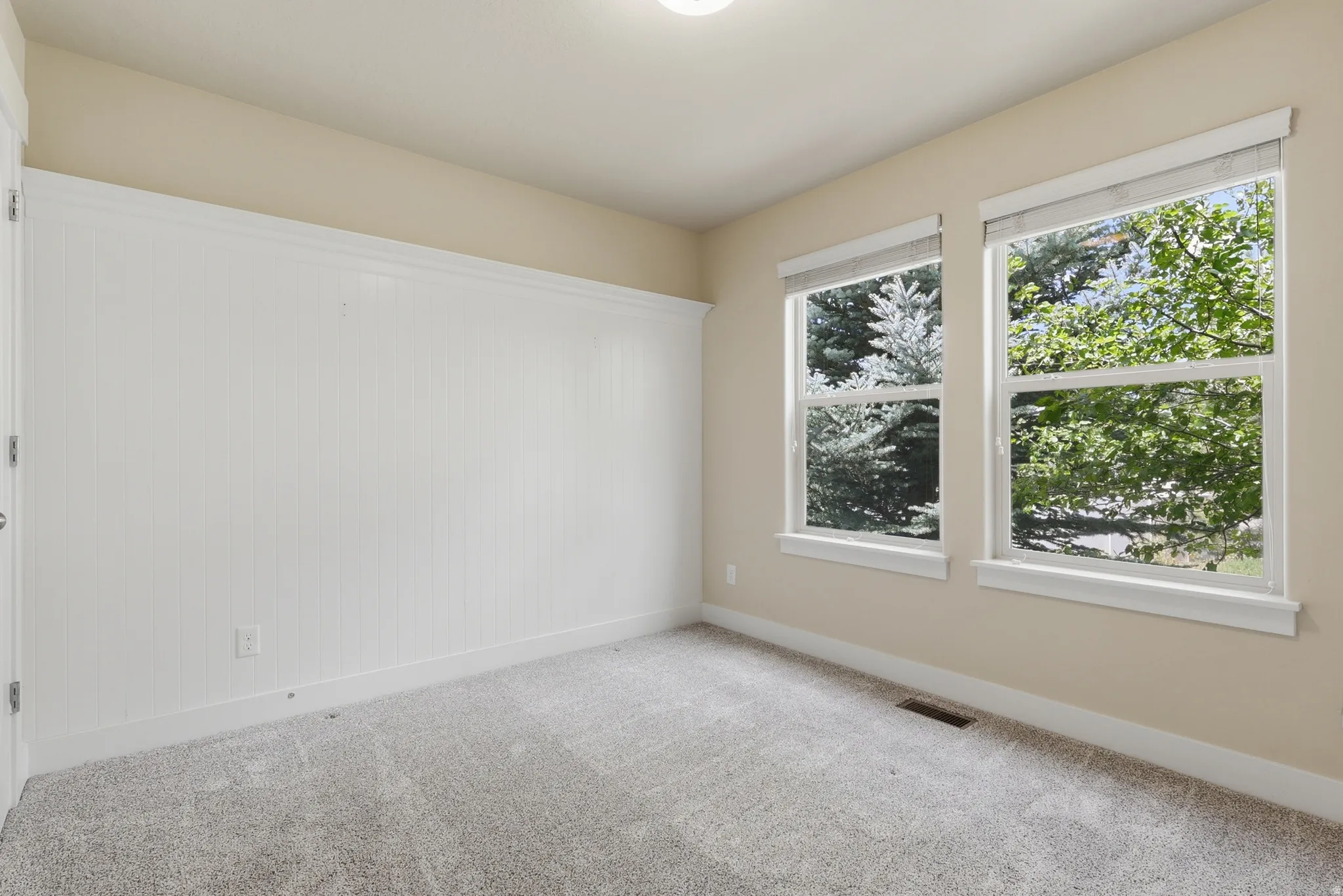 Spacious bedroom #2 featuring two large windows, light-colored carpeting, and a large closet.