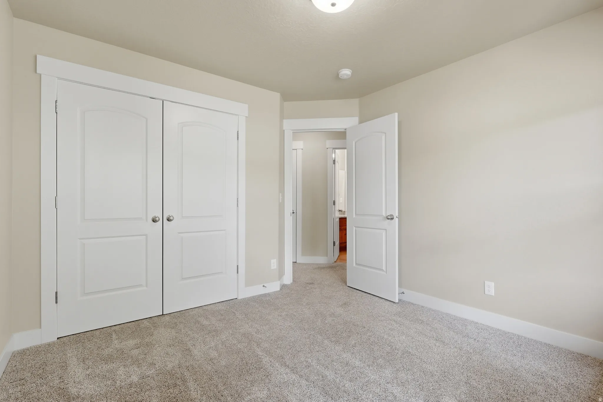 Spacious bedroom #2 featuring two large windows, light-colored carpeting, and a large closet.