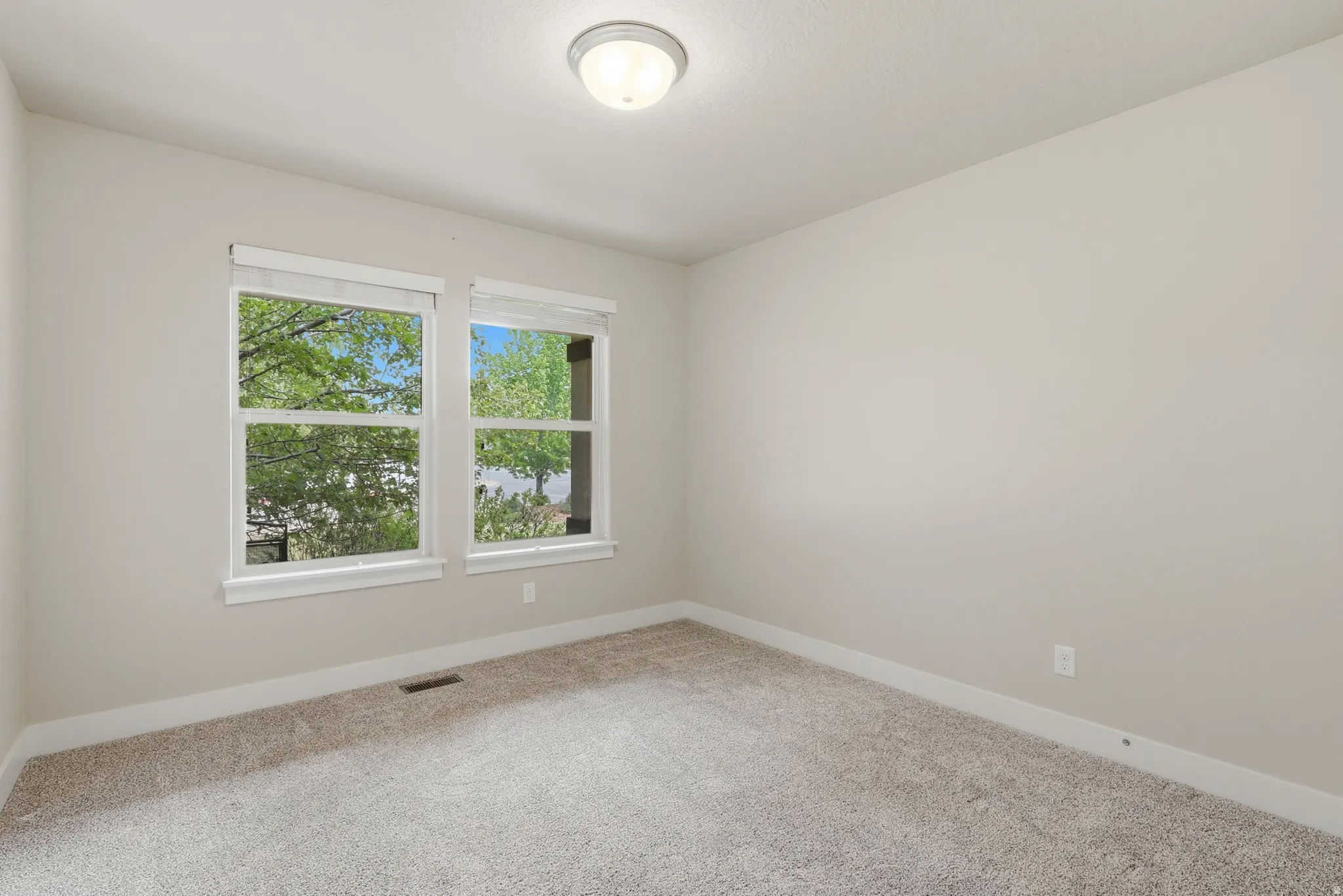 Spacious bedroom #3 featuring two large windows, light-colored carpeting, and a large closet.