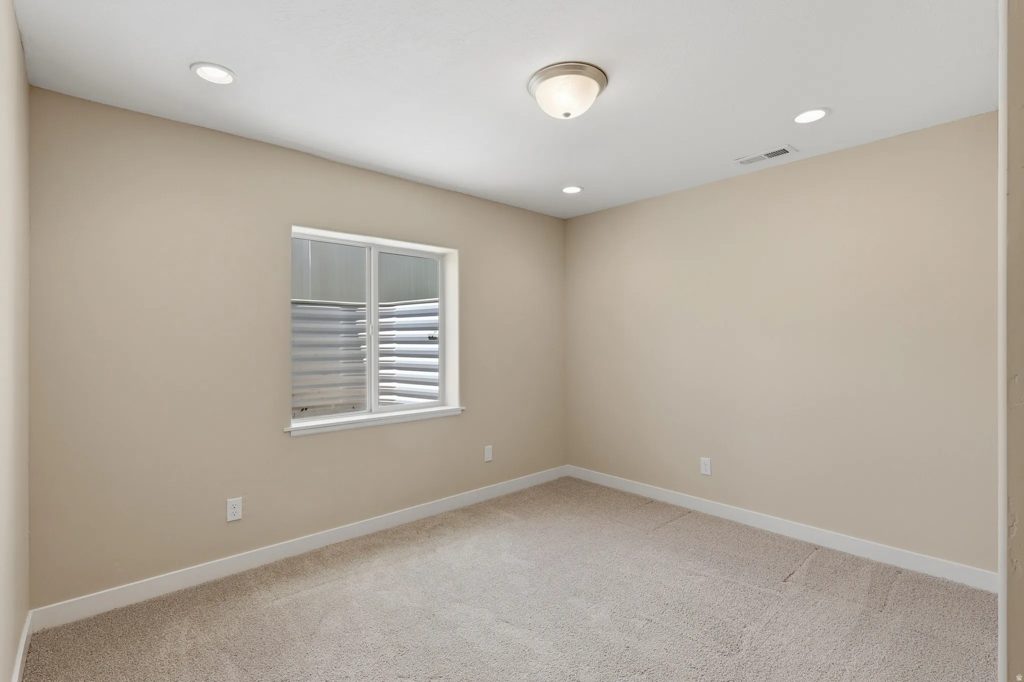 Spacious and light bedroom #4 with a large window and recessed and flush-mount lighting.