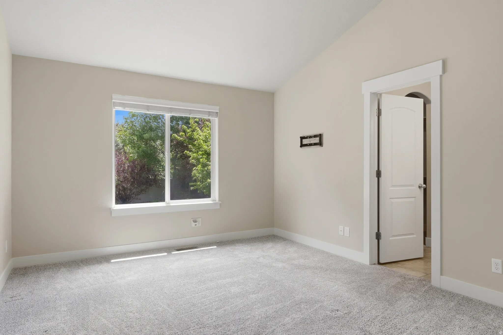 Spacious and light master suite featuring vaulted ceilings and neutral wall tones.
