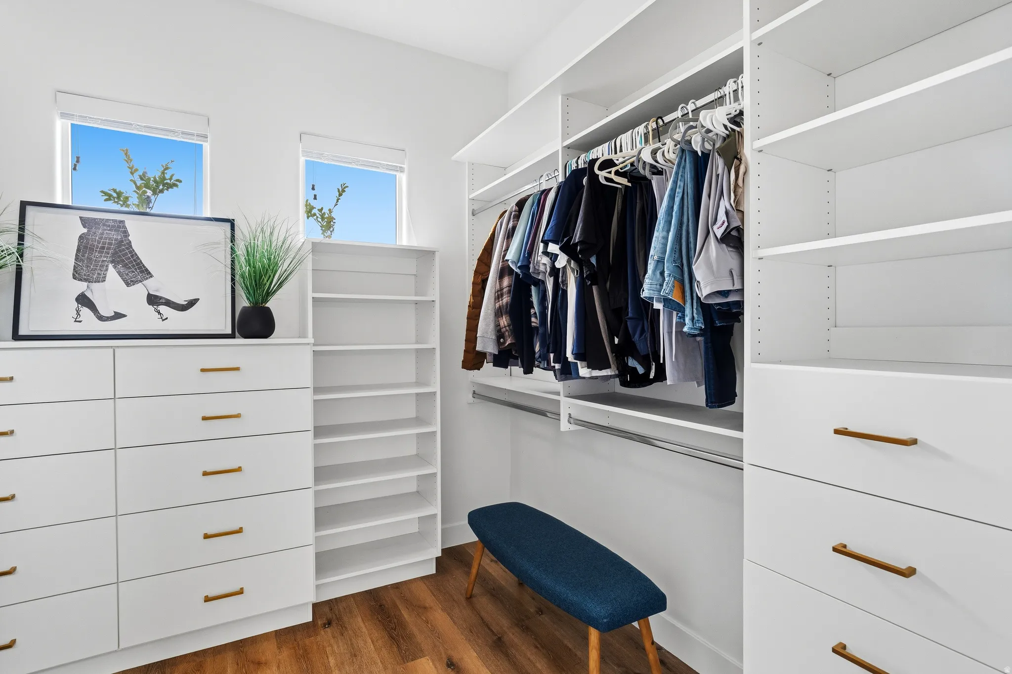 Custom closet system featuring white built-in cabinetry, shelving, and hanging rods.