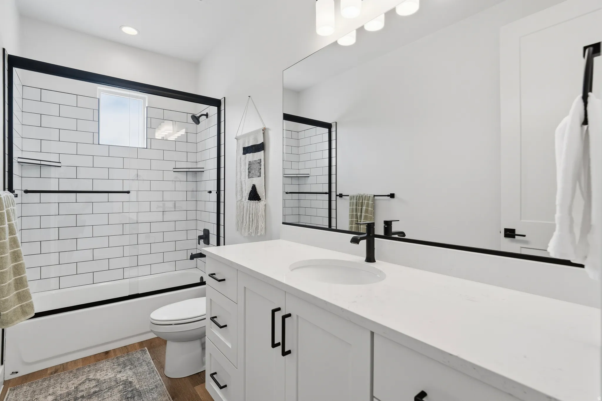 White subway tile shower surround with black-framed glass enclosure.