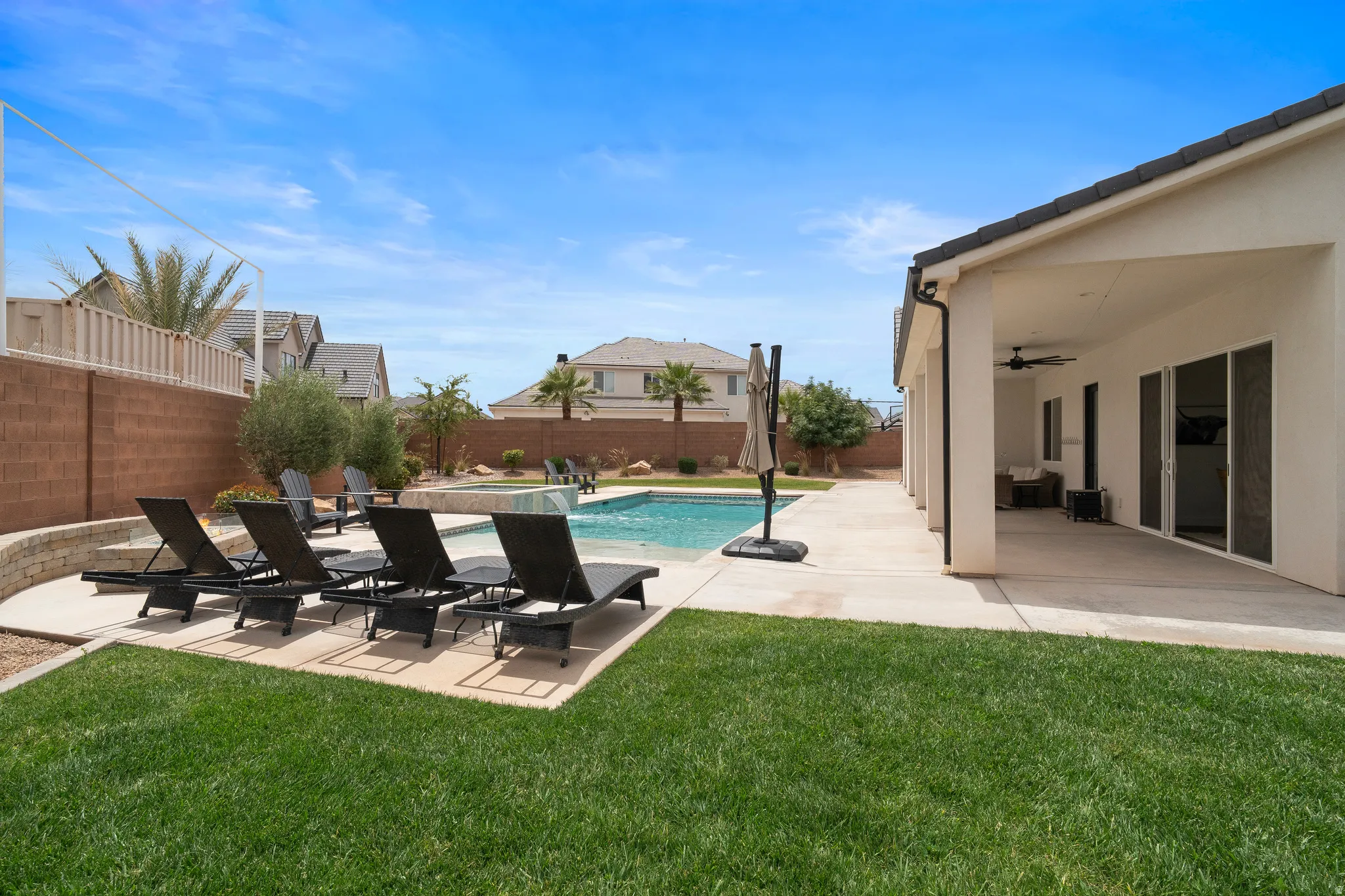 Expansive outdoor living area featuring a swimming pool, integrated spa, and concrete patio.
