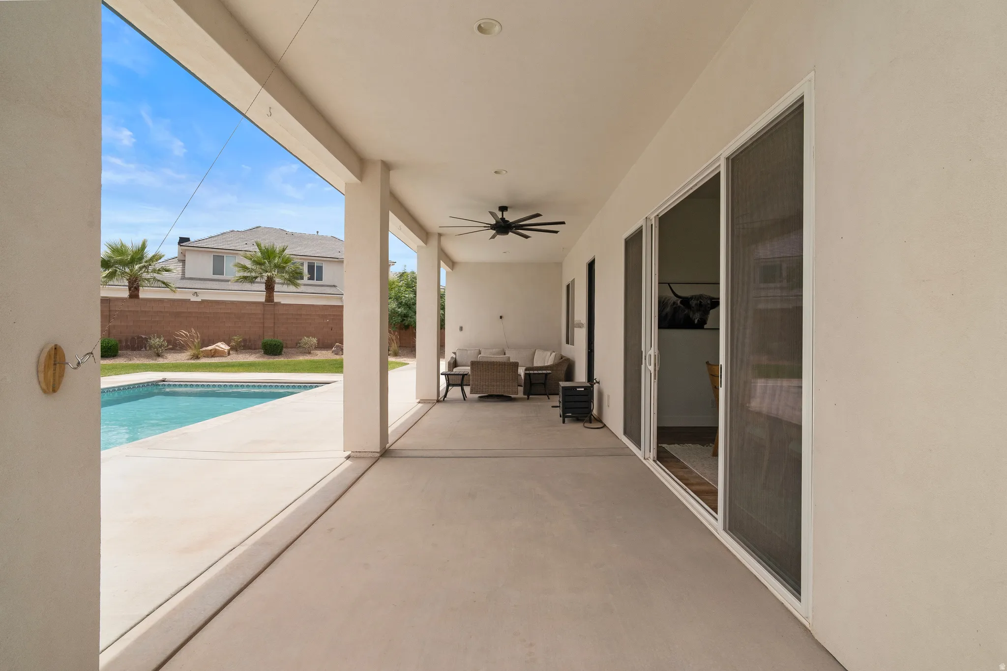 Covered patio with a concrete surface, featuring a ceiling fan, recessed lighting, and multiple sliding glass doors.