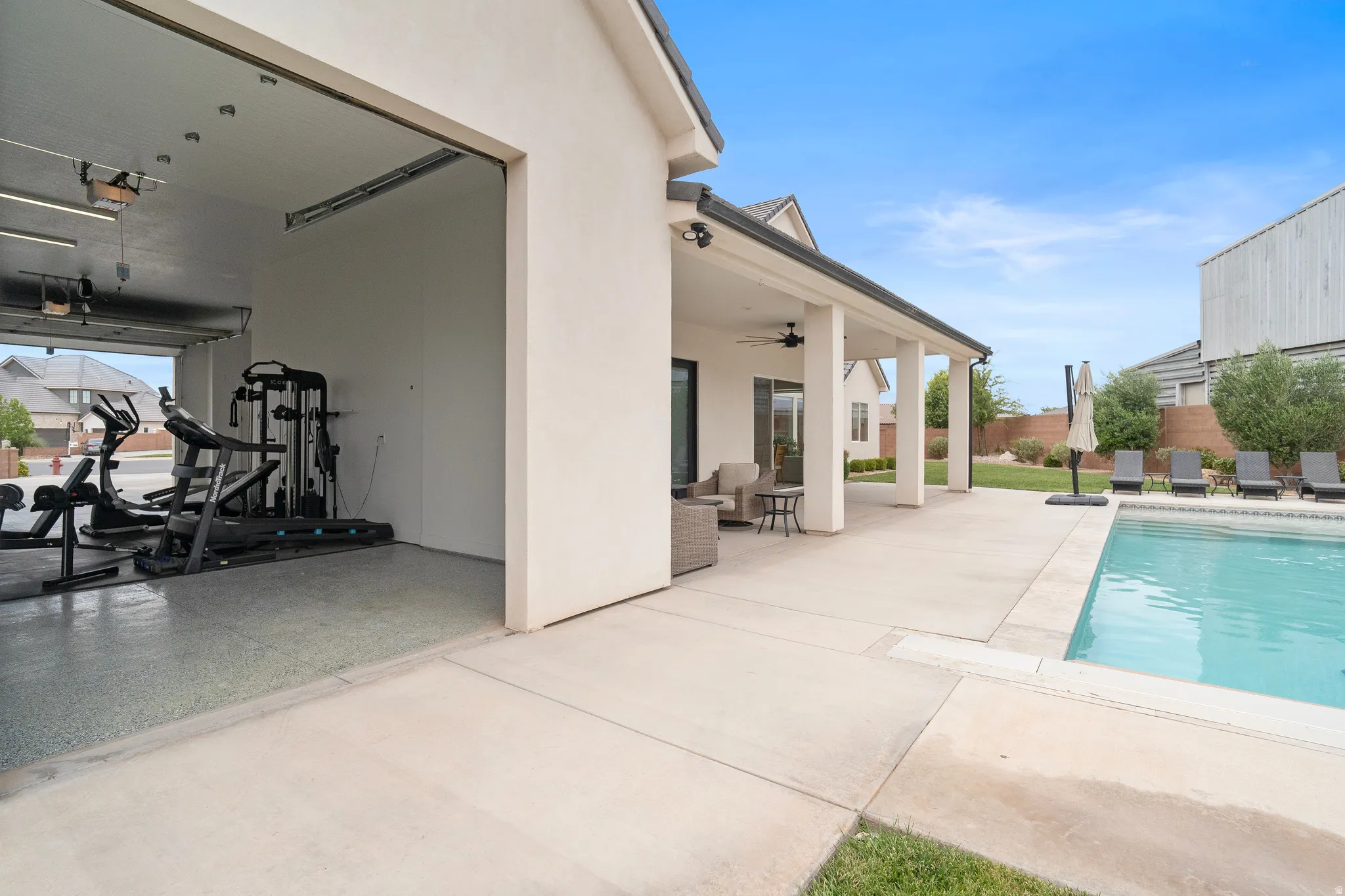 Outdoor living space featuring a covered patio, inground swimming pool, and concrete decking.