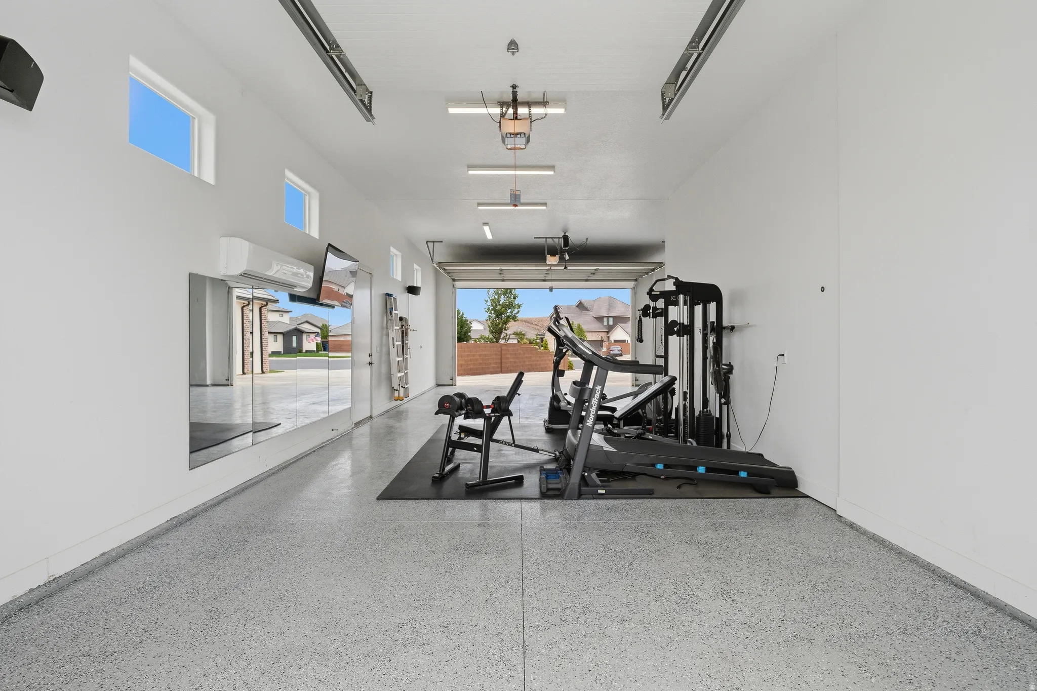 Spacious garage with epoxy flooring, white walls, and high ceilings.