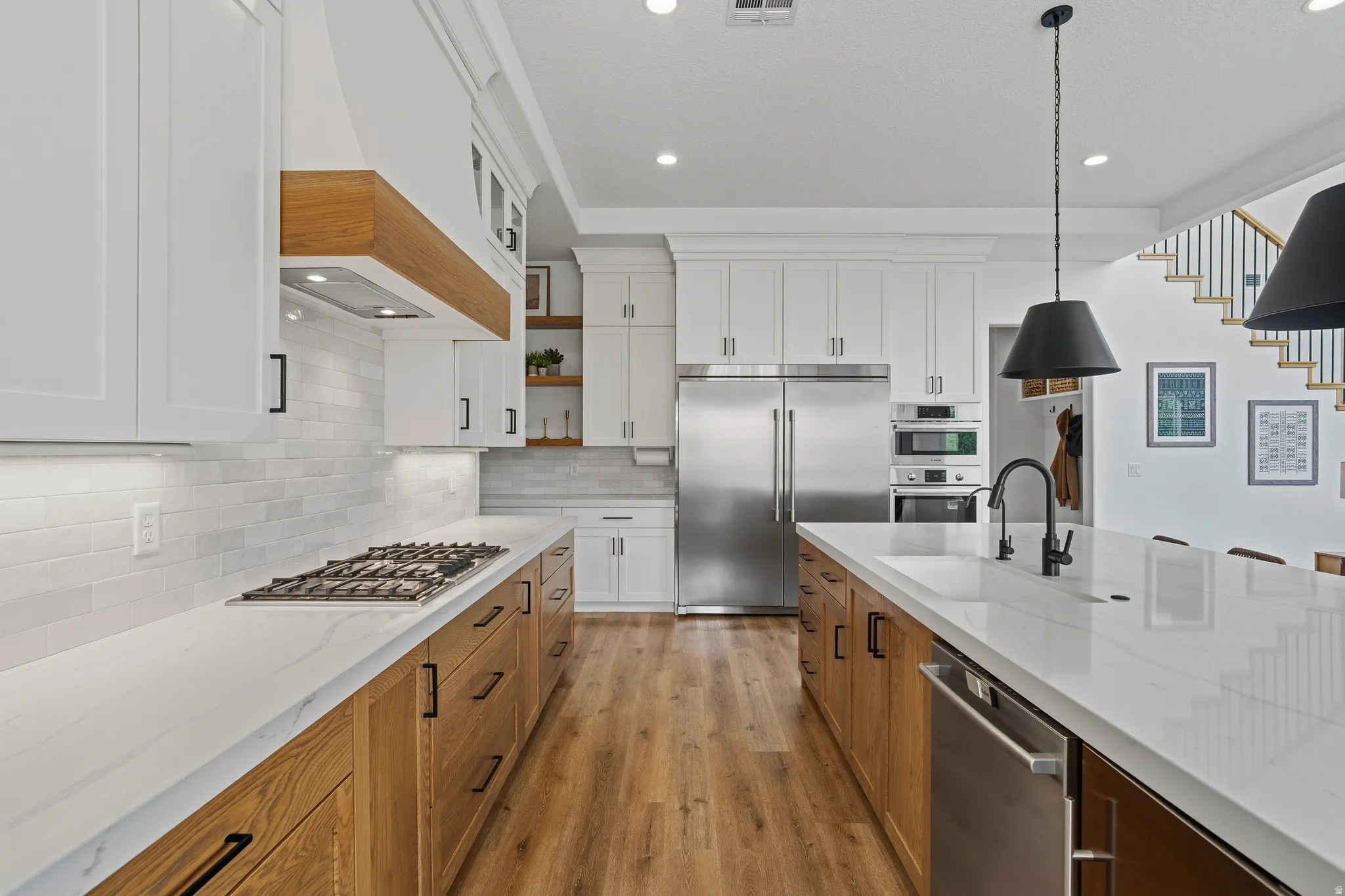 Spacious kitchen featuring white upper cabinetry, wood-finish lower cabinetry, and light-colored countertops.