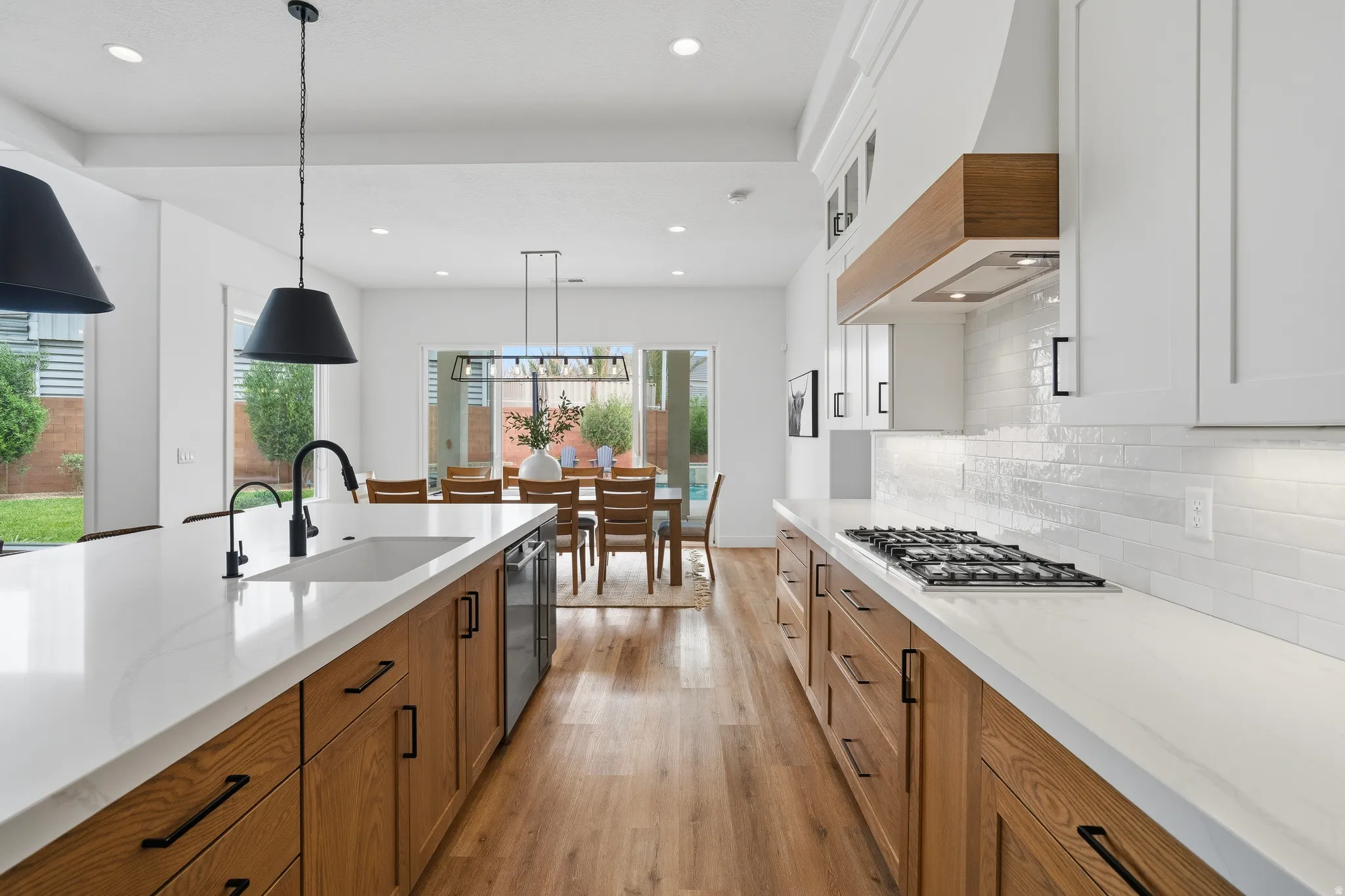Modern kitchen with light wood-finish cabinetry, white countertops, and a subway tile backsplash.