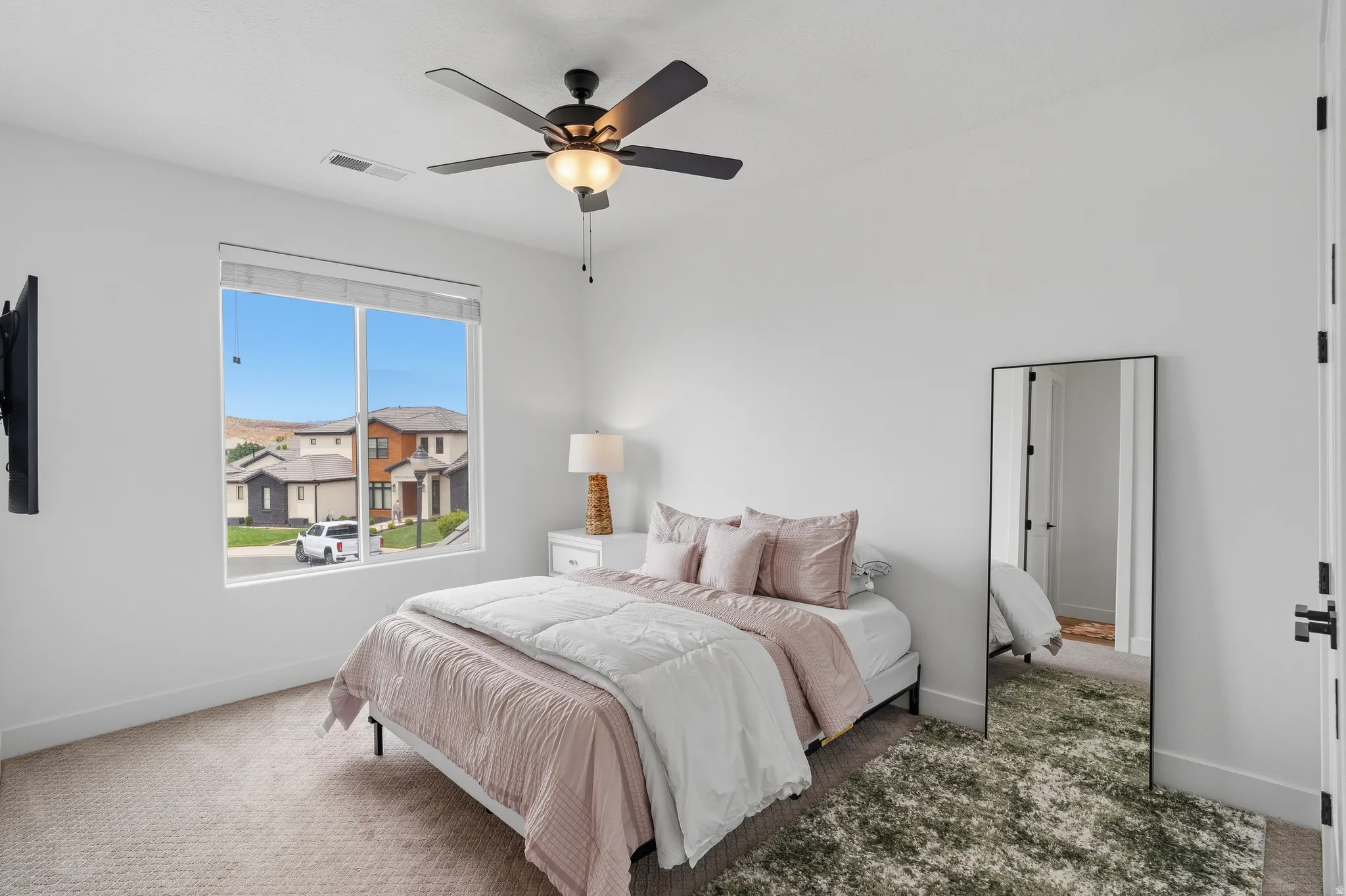 Bright bedroom featuring a large window, a ceiling fan with integrated lighting, recessed lighting, and soft carpet flooring