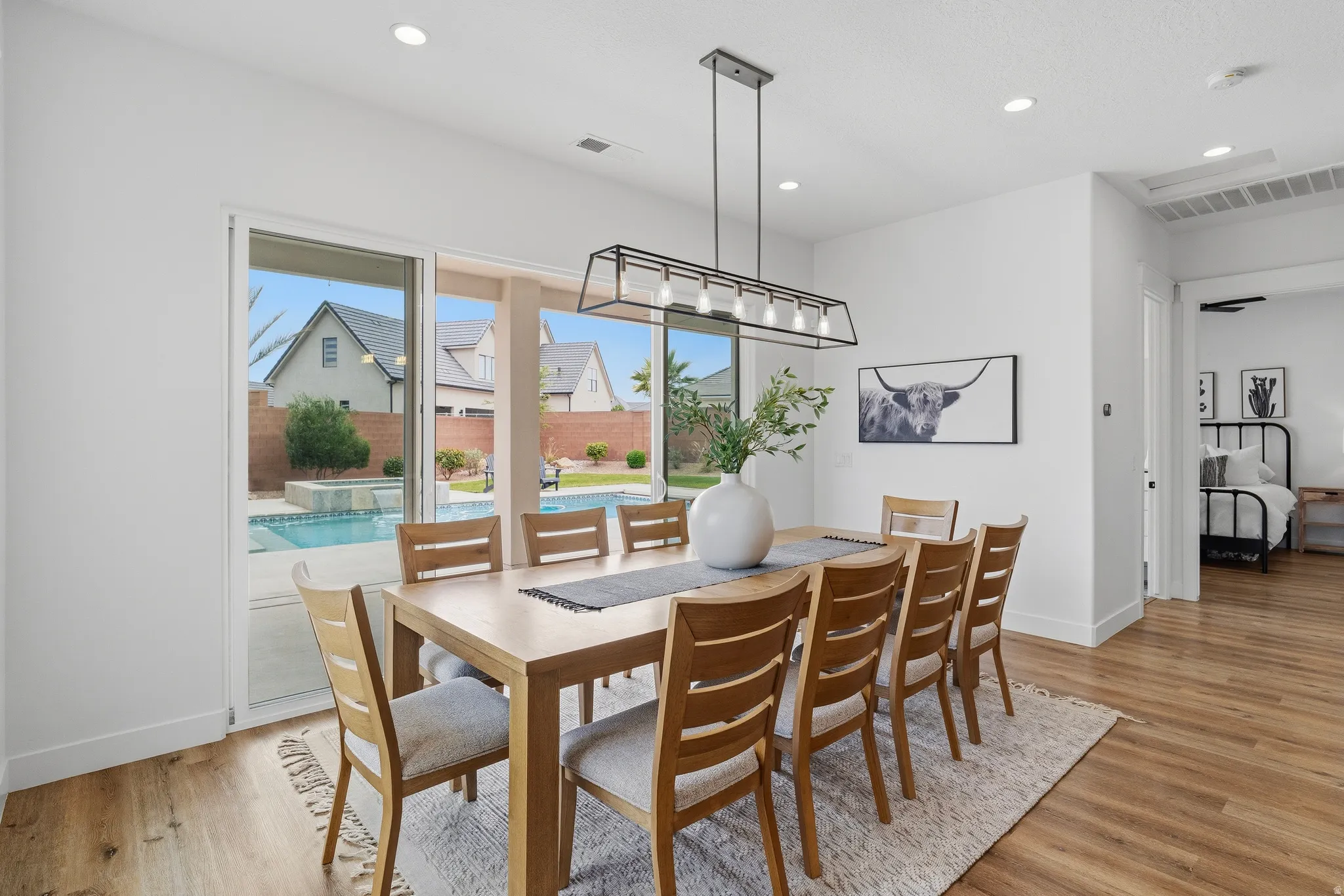 Spacious dining area featuring wood-finish flooring and a contemporary linear chandelier.