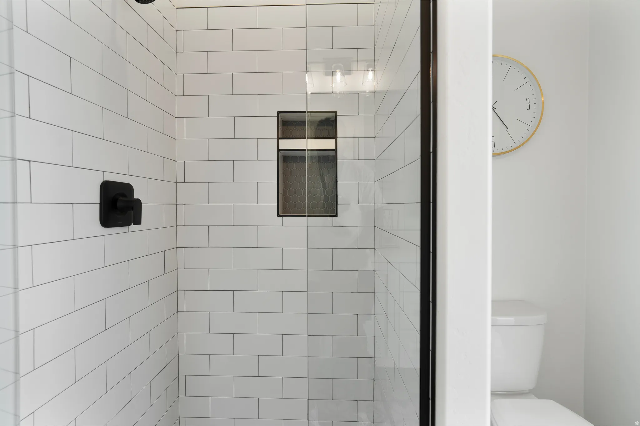Shower enclosure featuring subway tile walls, a built-in shower niche, and a matte black shower fixture.