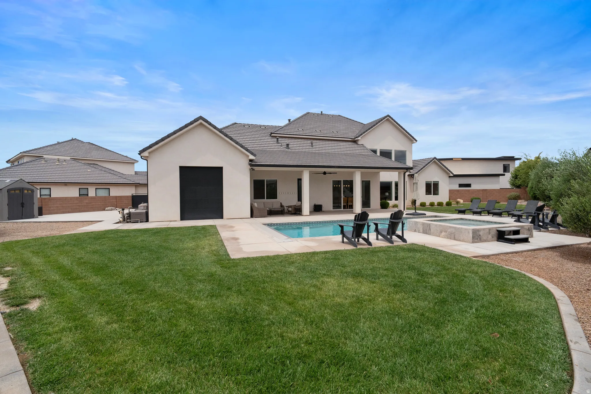 Expansive rear yard featuring a rectangular swimming pool, integrated spa, and a concrete patio surround.