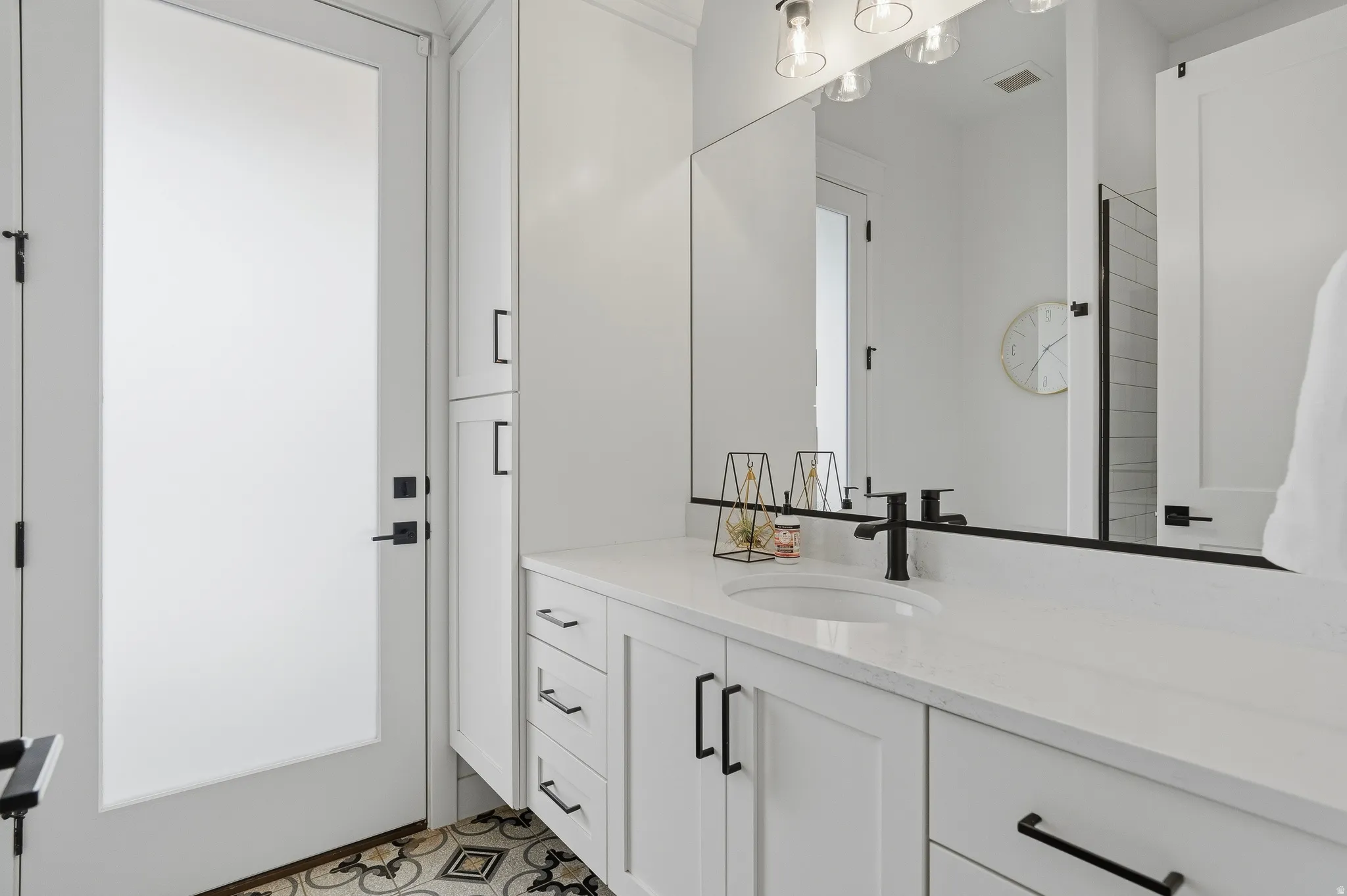 Bathroom vanity featuring an integrated sink, white countertop, and dark hardware.