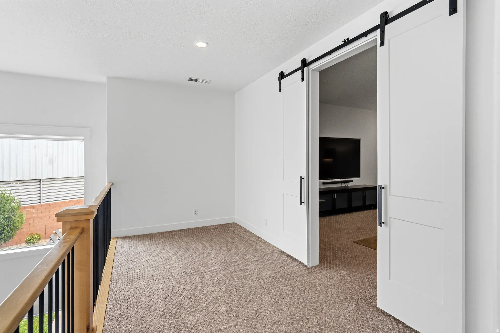 Loft area featuring a neutral carpet, white walls, and recessed lighting.