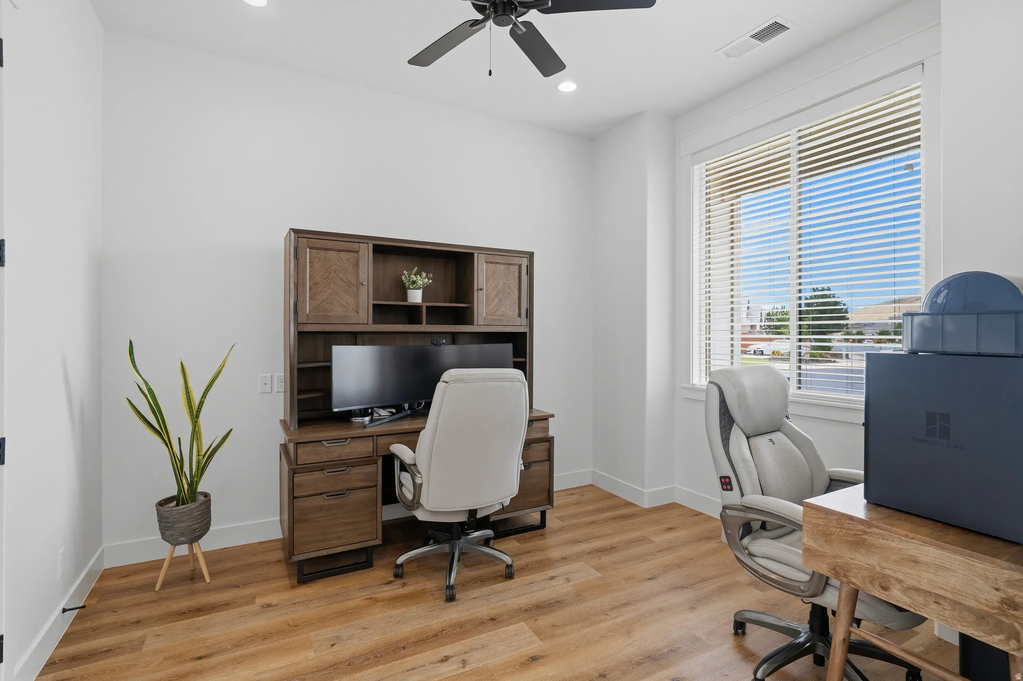 Bright room featuring a large window with blinds, wood-finish flooring, a ceiling fan, recessed lighting, and white baseboards.