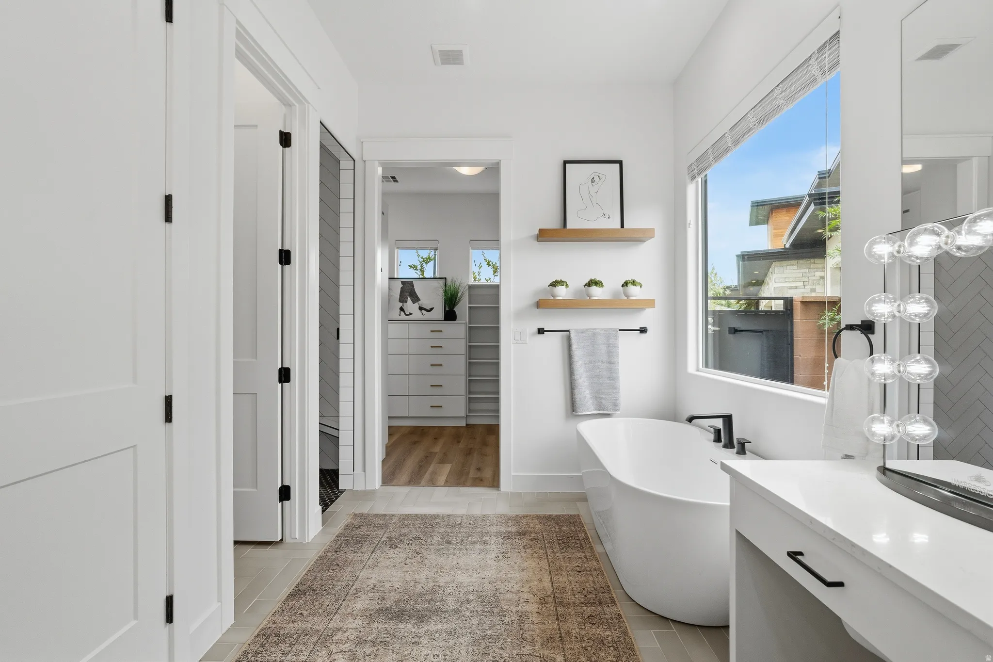 Freestanding soaking tub with matte black fixtures, complemented by a large window.