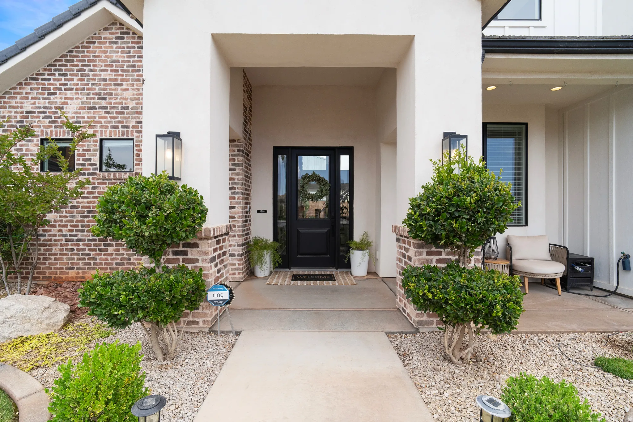 Entryway featuring a dark paneled door with glass inserts, flanked by matching exterior sconces.